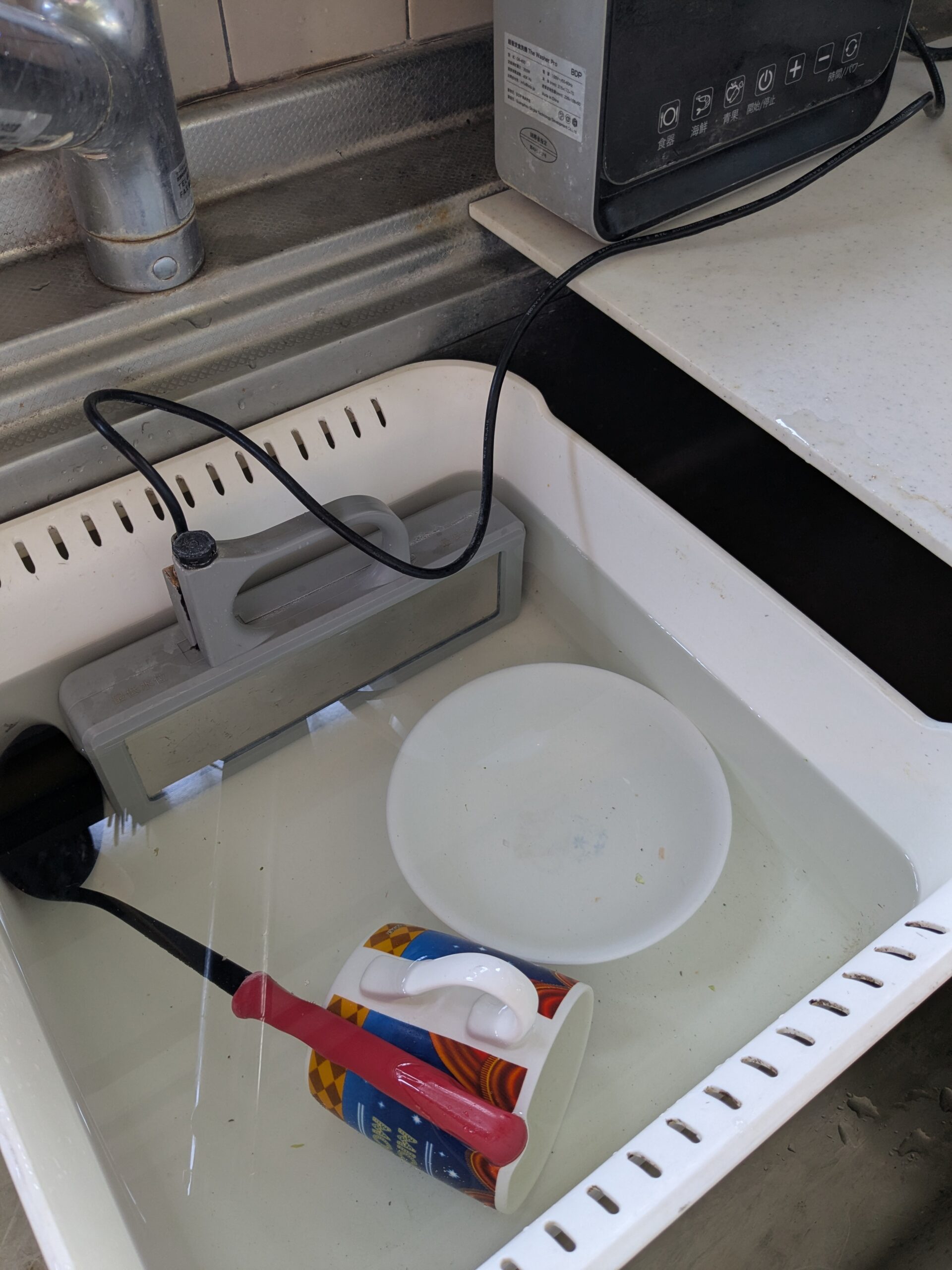 シンクに置いたたらいで食器を洗うWasherProと、カウンターの上の操作モニター