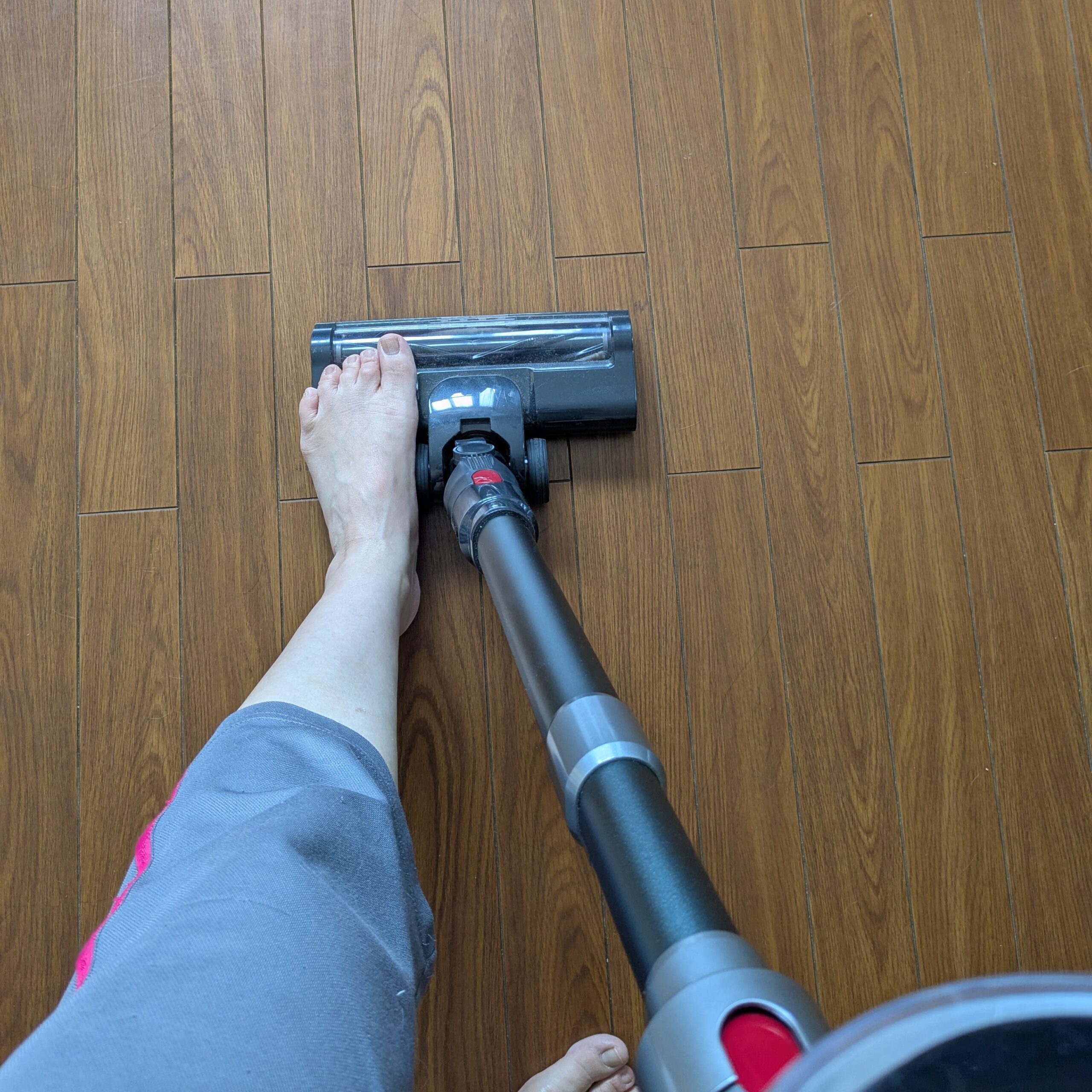 掃除機のヘッドを足で押さえて、本体を引き抜いているところ(手順2)