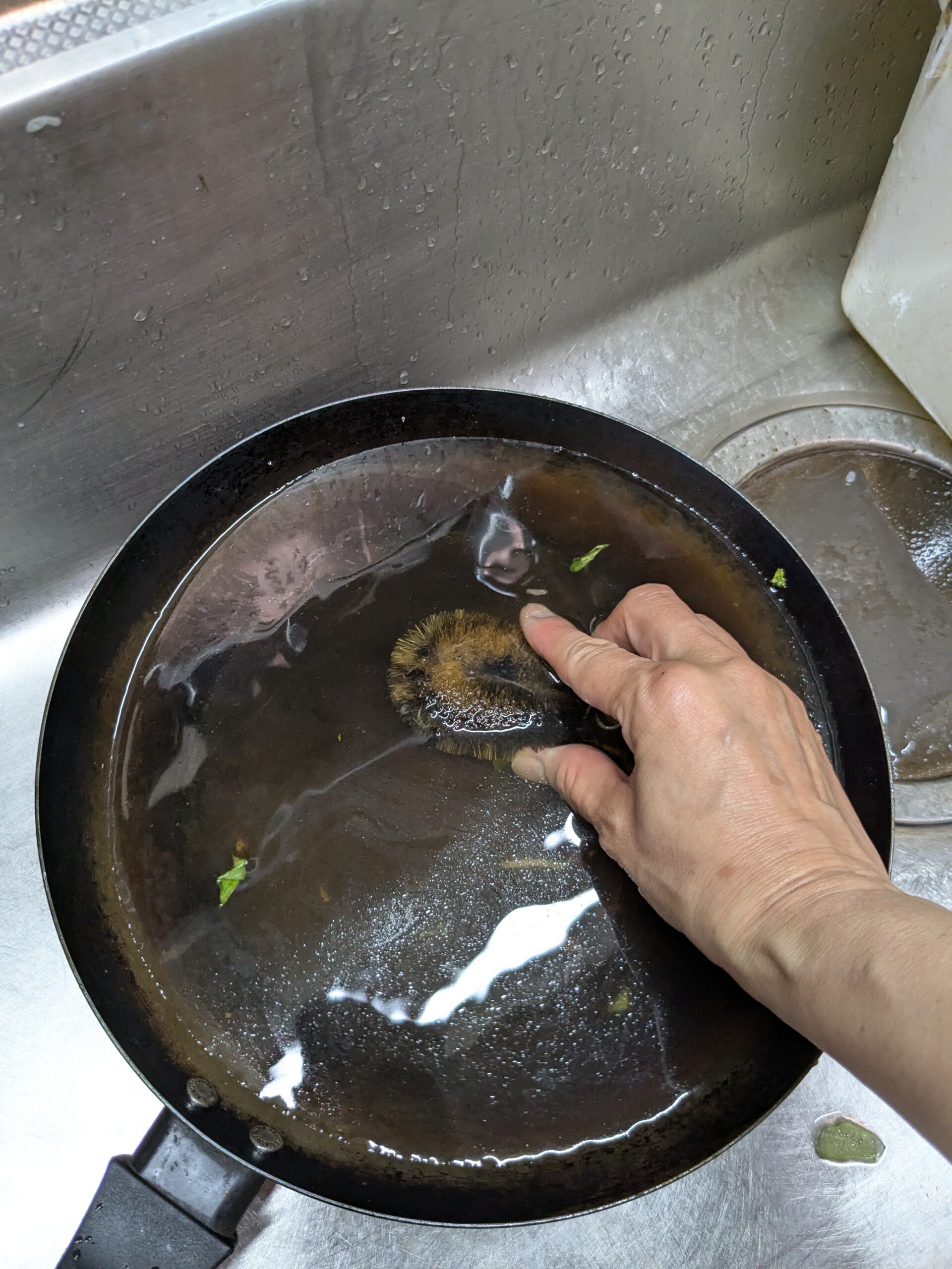 鉄フライパンをたわしで洗っているところ。洗剤は使わない
